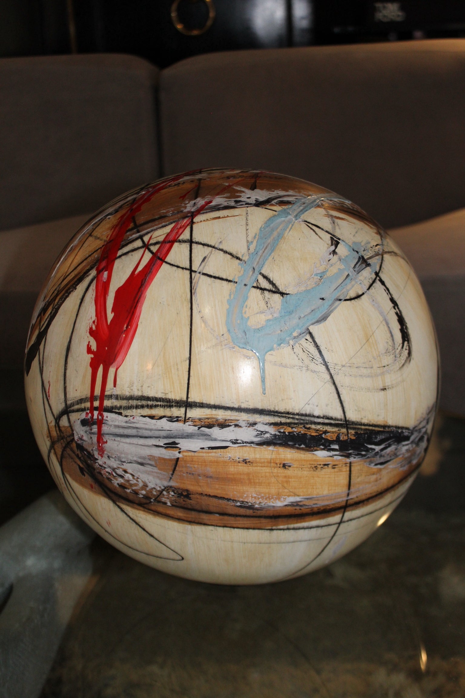 Scultura contemporanea 'Sfera di Colore' di Yuri Zatarain, sfera dipinta a mano con motivi astratti rossi, azzurri e neri.

