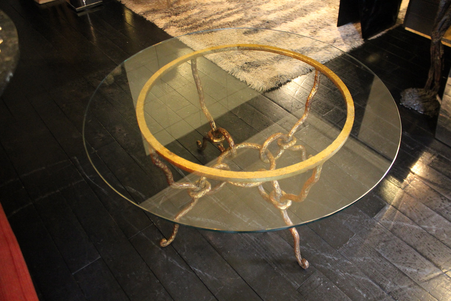 Tavolino modernariato anni '40 con piano in vetro e base scultorea in ferro battuto finitura oro.

