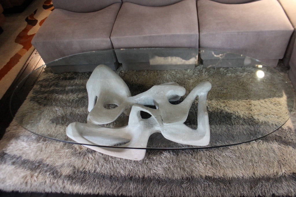 Tavolino modernariato anni '70 'Kanasutra' con piano ovale in vetro e base scultorea astratta in composito.

