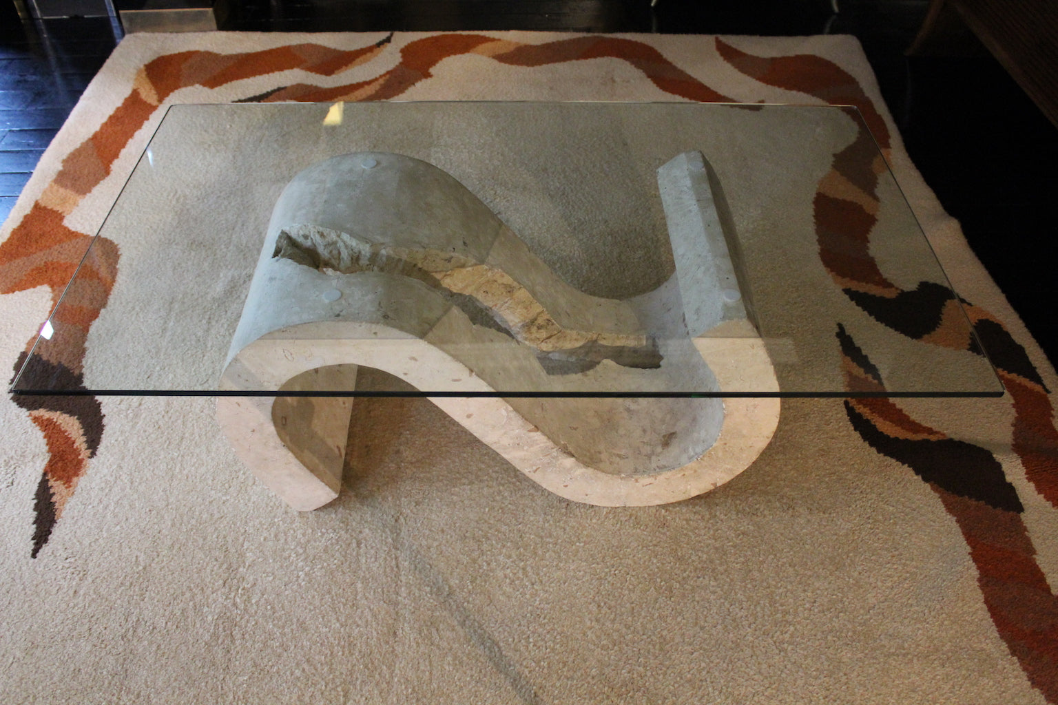 Tavolino modernariato anni '70 con piano in vetro e base scultorea a forma di 'S' in travertino grezzo.