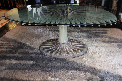 Tavolo da pranzo scultoreo 'Margherita' di Chelini Firenze, con base a forma di palma e piano in vetro ovale.

