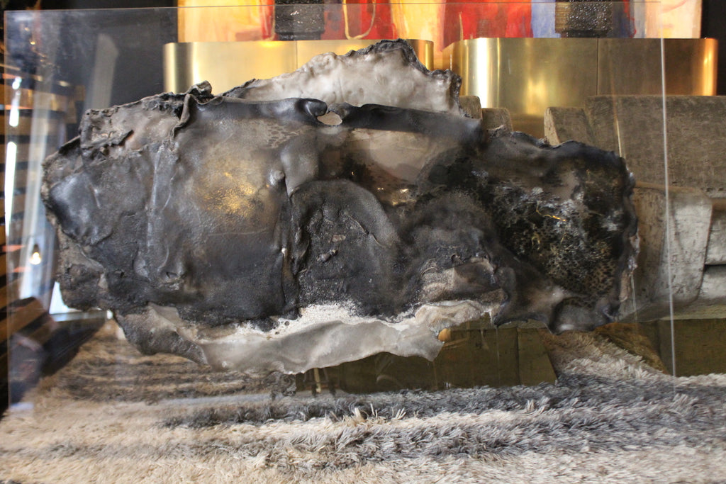 Pannello scultoreo astratto di L. Sonzini in resina lavorata, con finitura organica scura e bordi chiari.